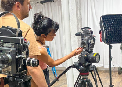 Two people setting up film cameras and lights to record